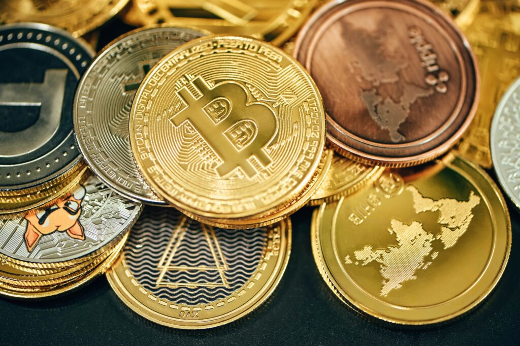 Várias moedas representando as criptomoedas e altcois, e no centro, a a principal, o Bitcoin